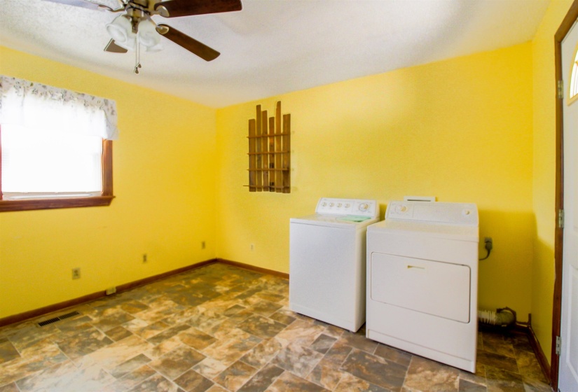 Laundry room with stone finish floors, a ceiling fan, and washing machine and dryer