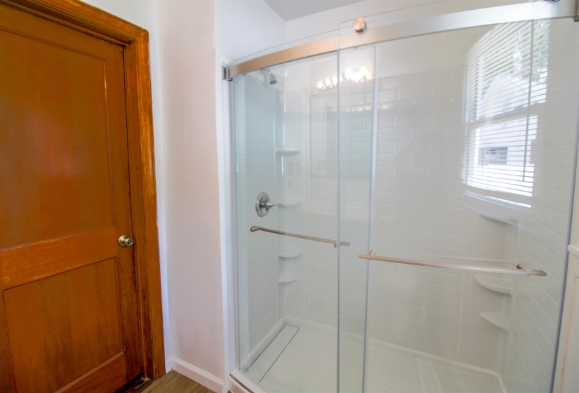 Bathroom with a shower stall and light wood-style flooring