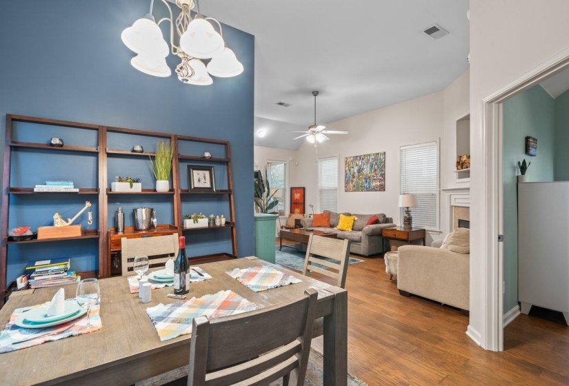 Dining area featuring ceiling fan, a fireplace, dark wood finished floors, and a chandelier