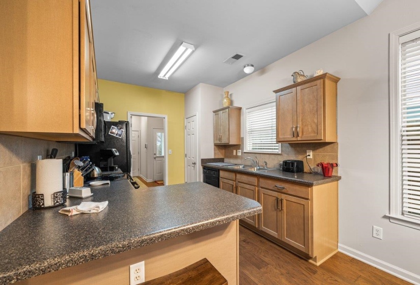 Kitchen with tasteful backsplash, dark countertops, dark wood-type flooring, range, and a peninsula