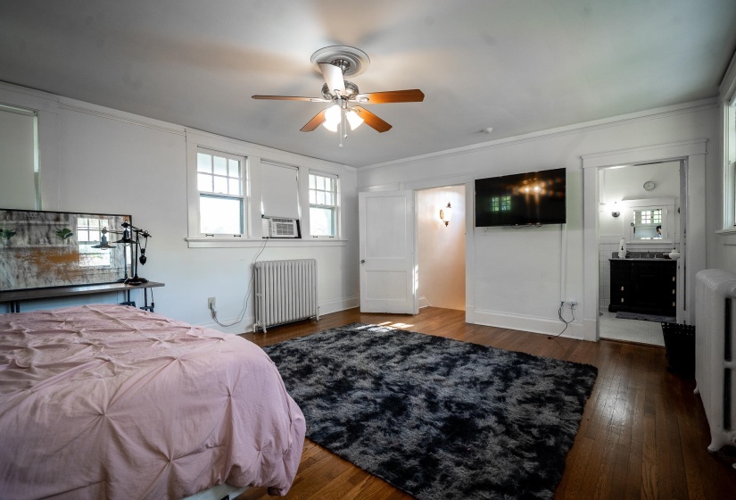 Bedroom with dark wood finished floors, radiator, ceiling fan, and crown molding
