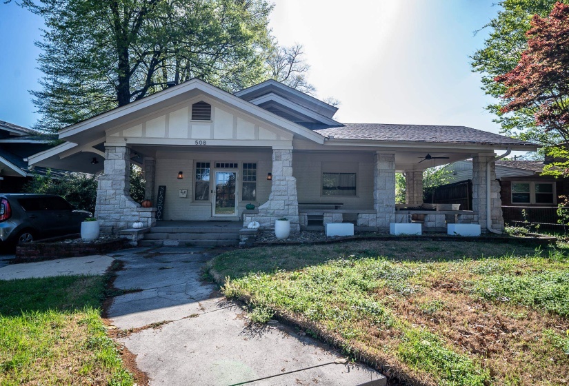 View of front of property featuring board and batten siding, a porch, stone siding, and a front lawn