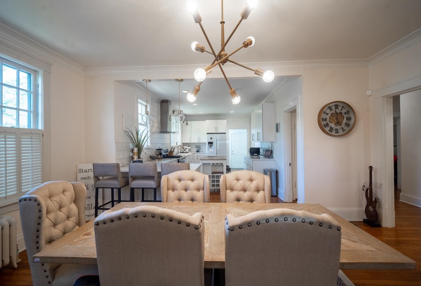 Dining area featuring dark wood finished floors, hanging lights, ornamental molding, healthy amount of natural light, and radiator