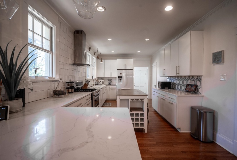 Kitchen featuring ornamental molding, white cabinets, plenty of natural light, light stone counters, and recessed lighting