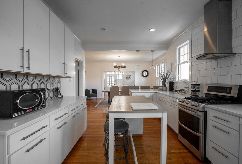 Kitchen featuring tasteful backsplash, range with two ovens, crown molding, and light stone counters