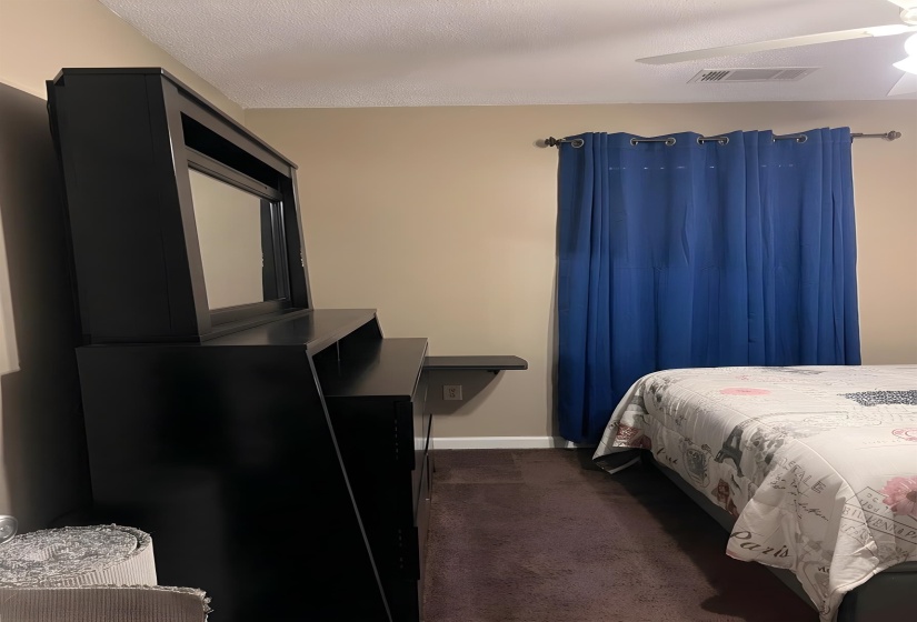 Bedroom with dark colored carpet and ceiling fan