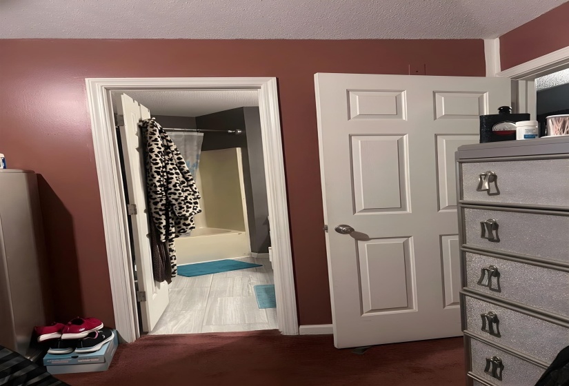 Hallway with a textured ceiling and dark colored carpet