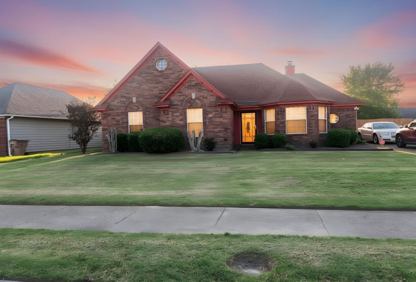View of front facade featuring a chimney, brick siding, and a yard