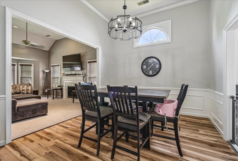 Dining room with a fireplace, crown molding, wood finished floors, suspended lighting, and ceiling fan