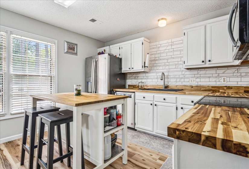 Kitchen featuring wood counters, white cabinetry, stainless steel appliances, light wood-style floors, and a textured ceiling