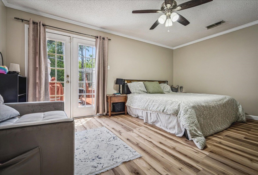 Bedroom with french doors, light wood finished floors, crown molding, a textured ceiling, and access to exterior