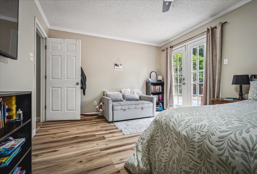 Bedroom with a textured ceiling, french doors, crown molding, light wood finished floors, and access to outside