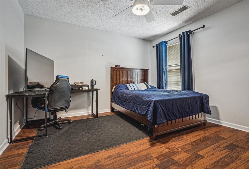 Bedroom featuring dark wood finished floors, ceiling fan, a textured ceiling, and an office area
