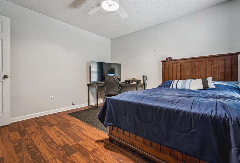 Bedroom featuring an office area, wood finished floors, a textured ceiling, and ceiling fan