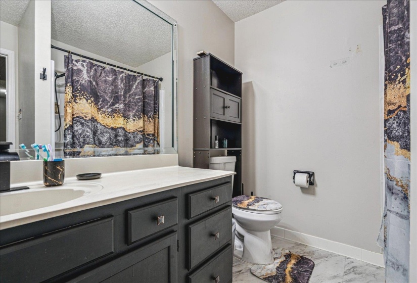 Bathroom featuring a shower with shower curtain, vanity, a textured ceiling, and light marble finish flooring