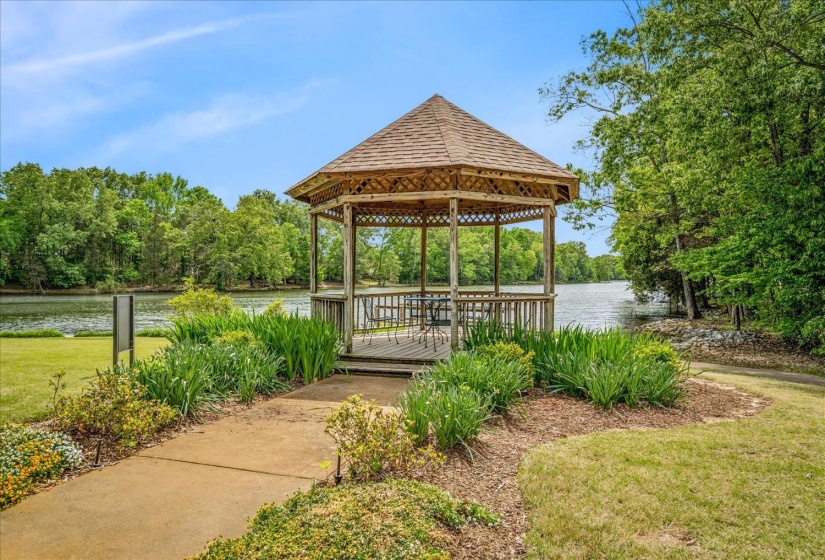 View of community featuring a gazebo, view of scattered trees, and a deck with water view
