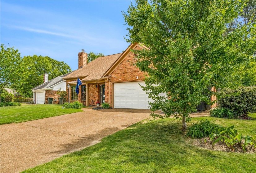 View of front of property with brick siding, a front lawn, a garage, a chimney, and driveway