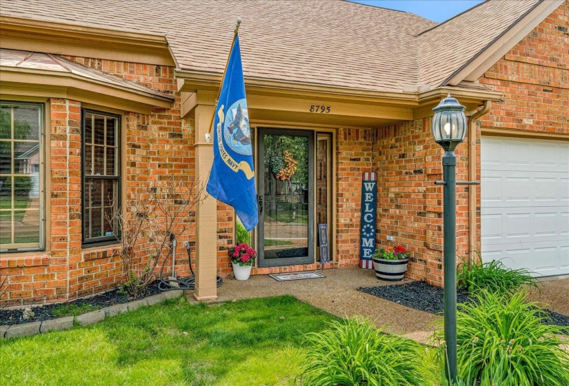 Entrance to property featuring a shingled roof, brick siding, and an attached garage