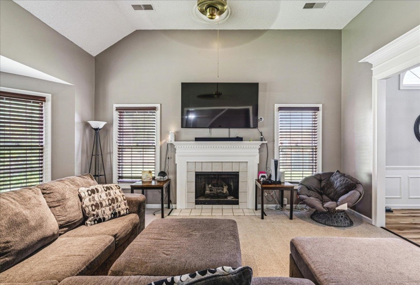 Carpeted living room featuring a tile fireplace and a high textured ceiling
