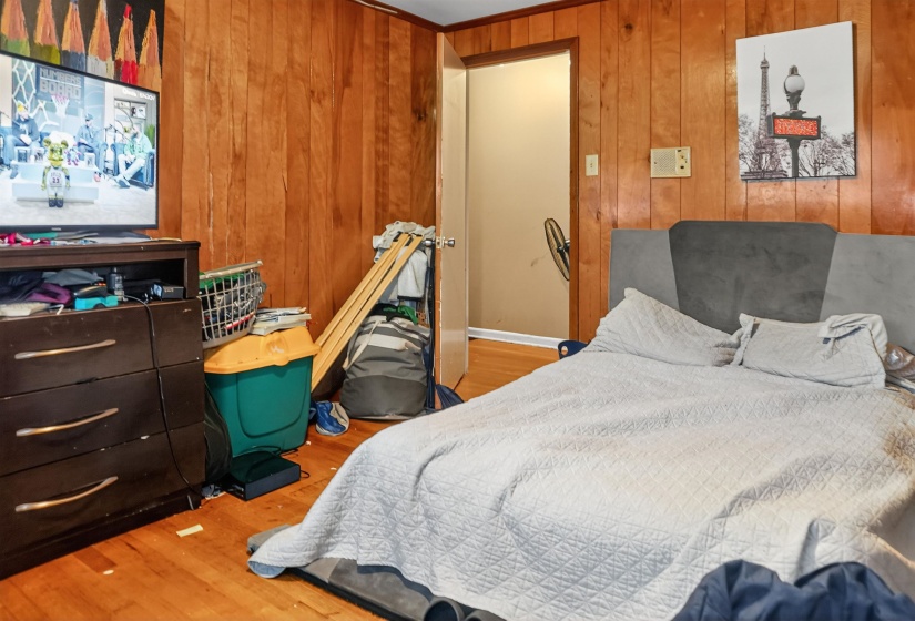Bedroom with light wood-type flooring and wood walls