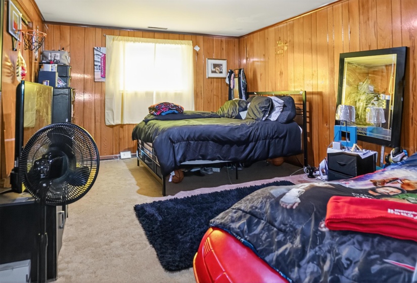 Carpeted bedroom featuring wood walls