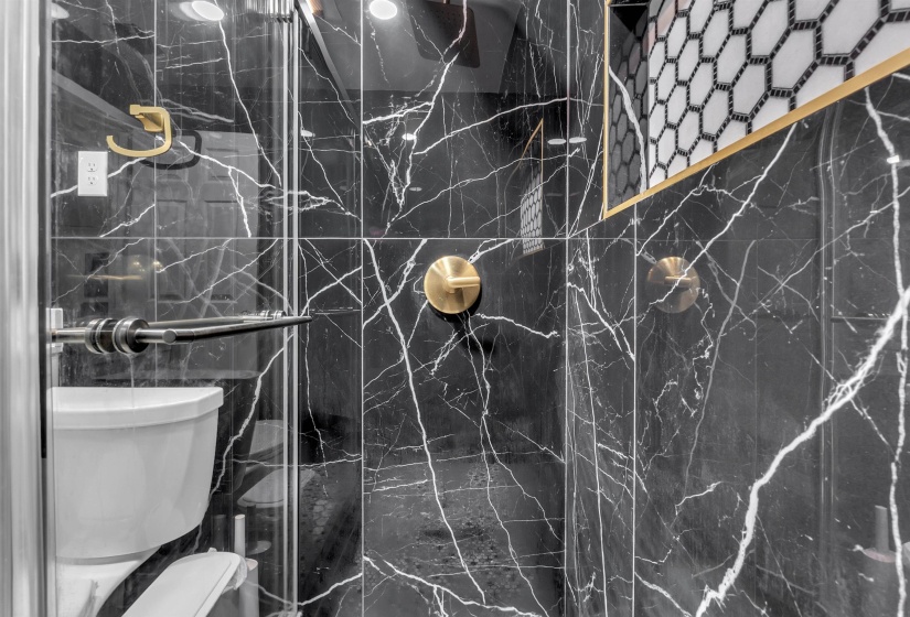 Bathroom featuring a marble finish shower and tile walls