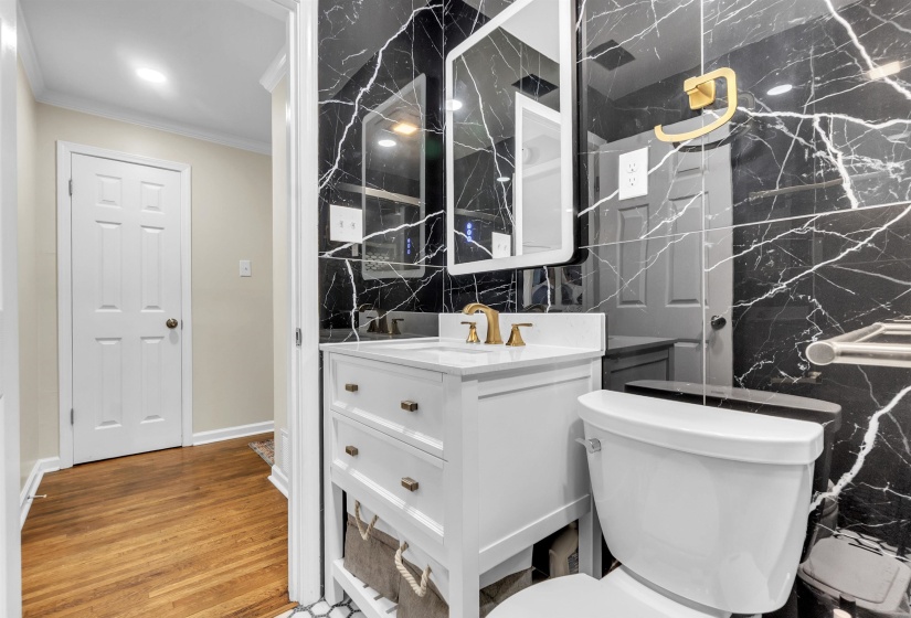 Half bath featuring ornamental molding, vanity, tile walls, and light wood-type flooring