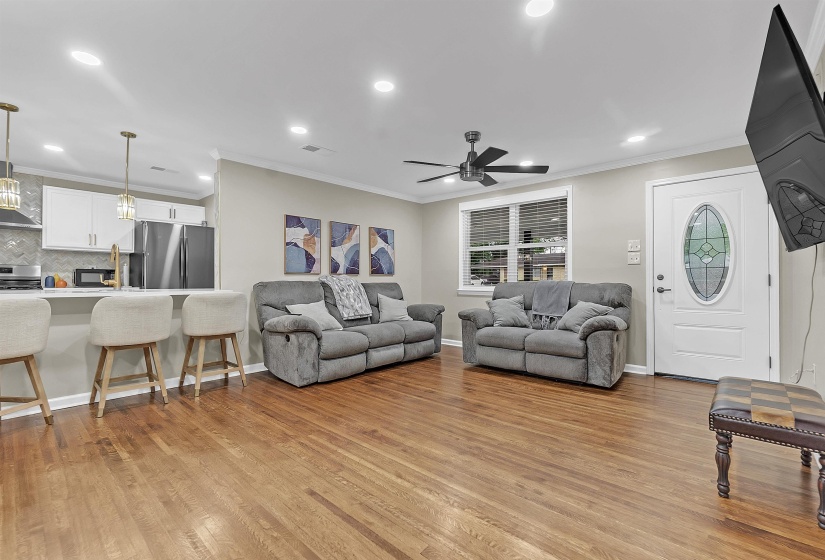 Living area featuring crown molding, light wood-type flooring, recessed lighting, and a ceiling fan