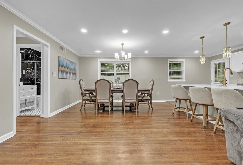 Dining area featuring light wood-style flooring, ornamental molding, and suspended lighting