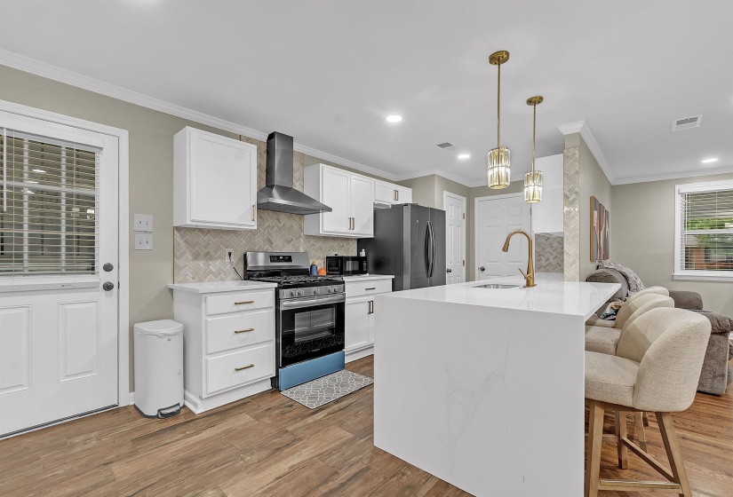 Kitchen featuring a breakfast bar area, stainless steel appliances, white cabinetry, backsplash, and ornamental molding