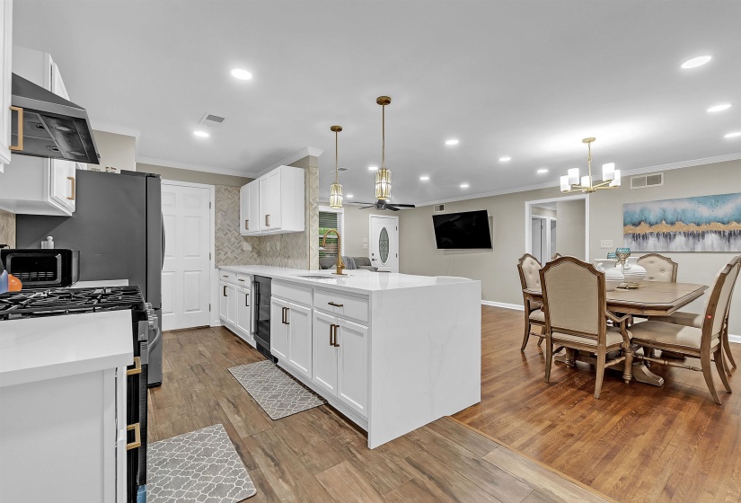 Kitchen with a peninsula, white cabinets, light stone counters, stainless steel appliances, and light wood-type flooring
