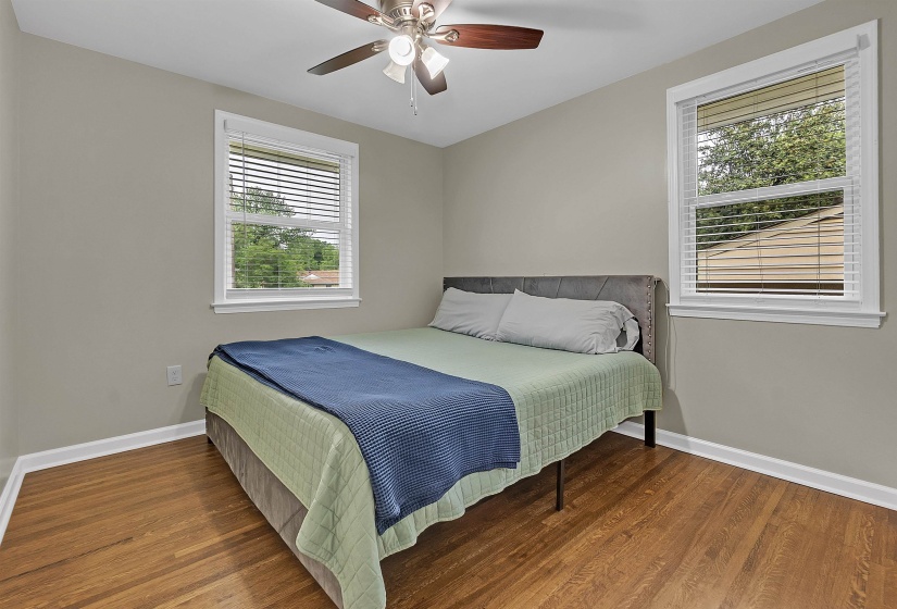 Bedroom with wood finished floors, a ceiling fan, and multiple windows