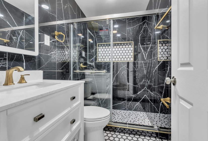 Full bath with tile walls, vanity, and a marble finish shower