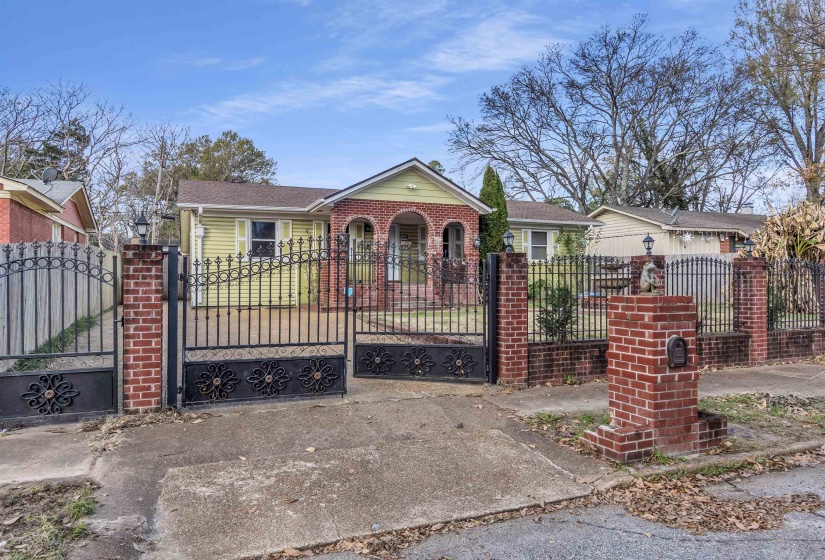 View of front of home featuring a fenced front yard, a gate, brick siding, and a shingled roof