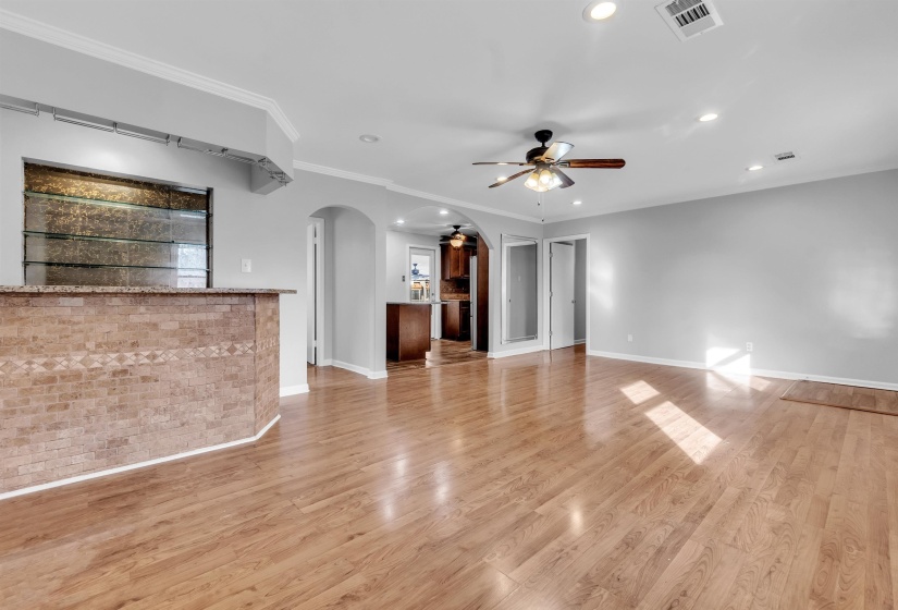 Unfurnished living room with ceiling fan, light wood-style floors, recessed lighting, arched walkways, and ornamental molding