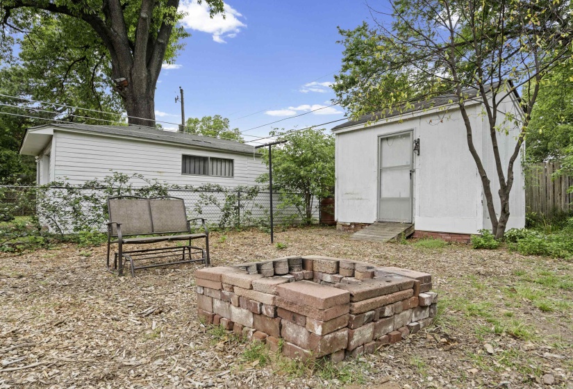 Fenced backyard with an outdoor fire pit and a shed