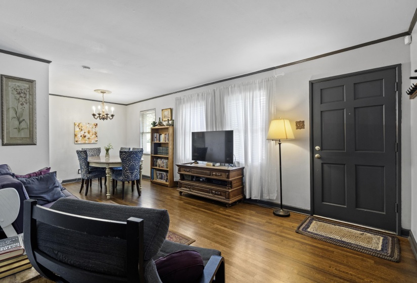 Living area featuring dark wood-style floors, crown molding, and a chandelier
