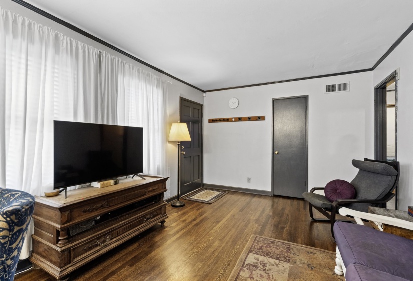 Living room featuring dark wood-type flooring and crown molding