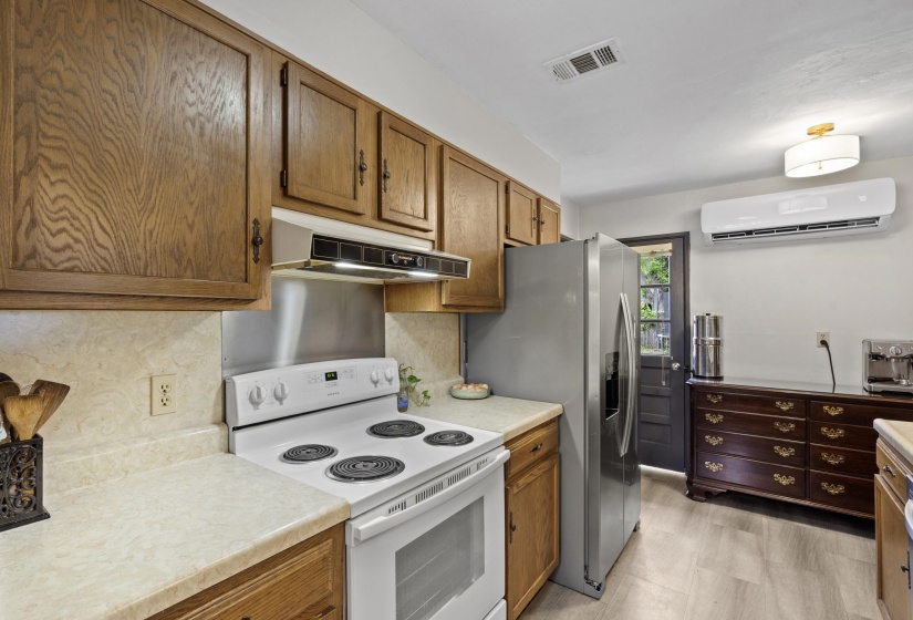 Kitchen featuring white range with electric cooktop, light countertops, stainless steel fridge with ice dispenser, and wood finish cabinetry