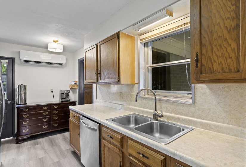 Kitchen featuring light countertops, backsplash, dishwasher, and wood finish cabinets