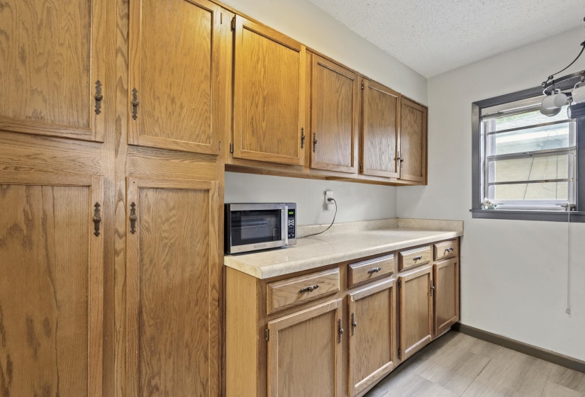 Kitchen with light countertops, stainless steel microwave, a textured ceiling, and wood finish cabinetry