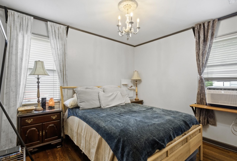Bedroom featuring dark wood-type flooring, hanging lights, crown molding, and cooling unit