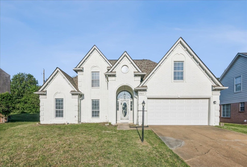 View of front of house with driveway, a front yard, and brick siding