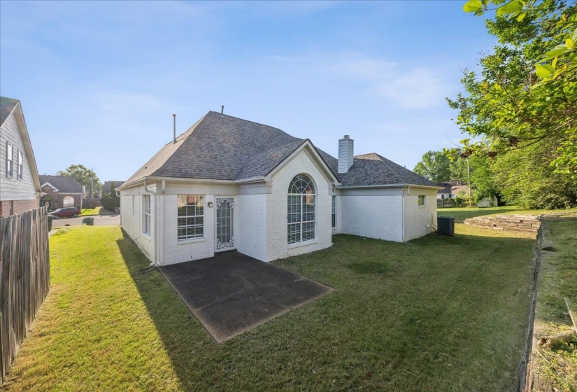 Back of property with brick siding, a yard, a patio area, and a chimney