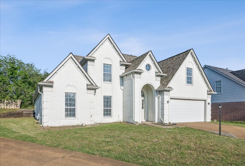 View of front of house featuring a front yard, concrete driveway, brick siding, and a garage