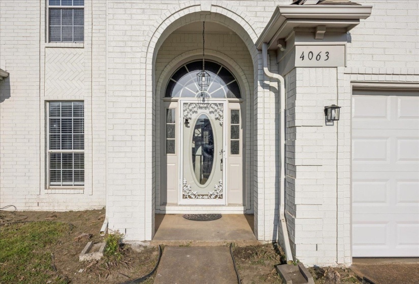 View of exterior entry featuring brick siding and a garage