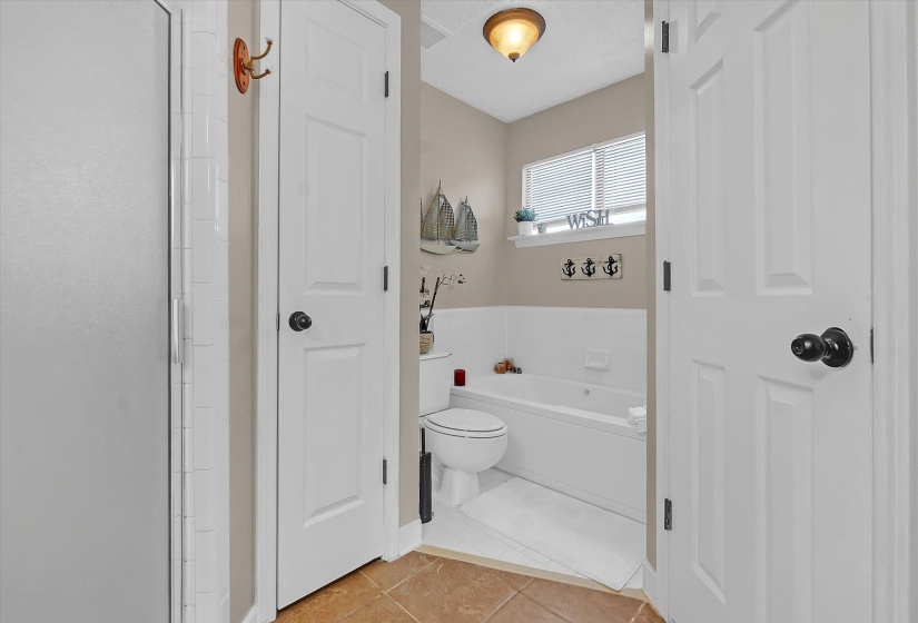 Bathroom with light tile patterned flooring, a bath, and a closet