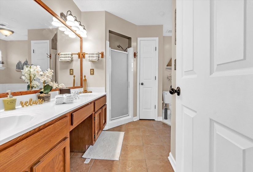 Bathroom with double vanity, a stall shower, and light tile patterned flooring