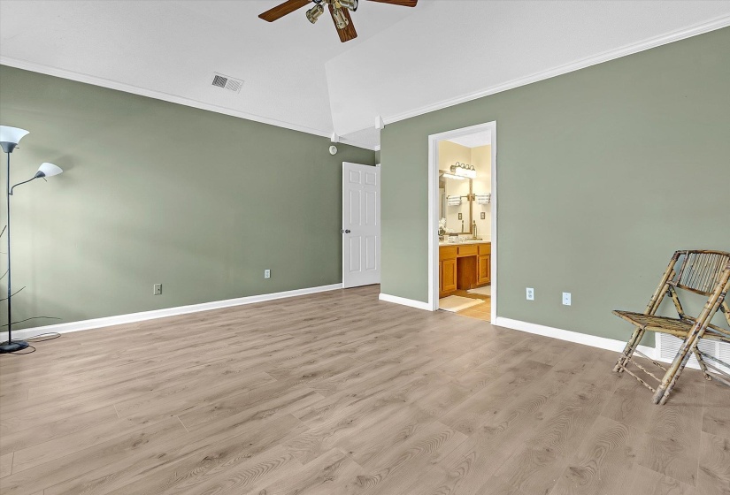 Unfurnished bedroom with ornamental molding, light wood-style flooring, ceiling fan, and connected bathroom