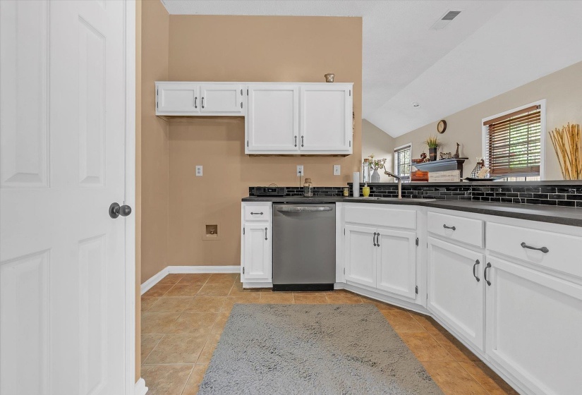 Kitchen featuring lofted ceiling, dishwasher, white cabinets, and light tile patterned floors